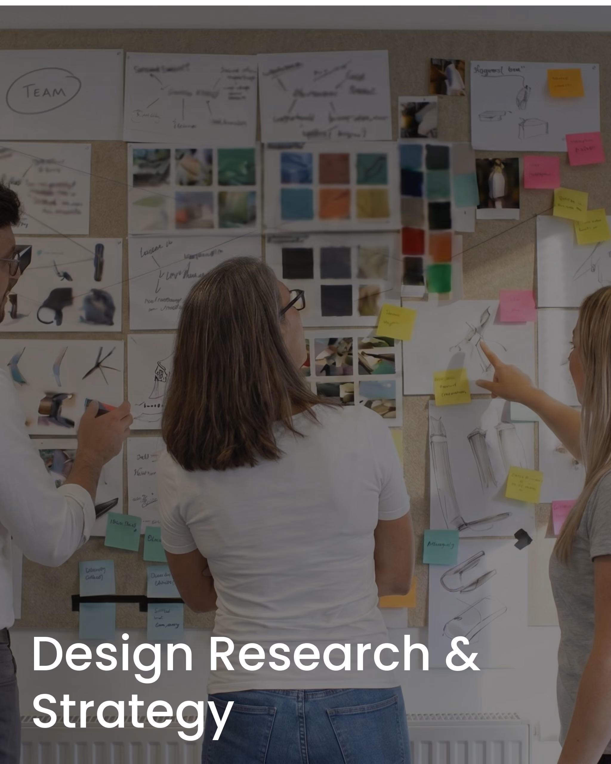 Three people analyzing sketches, color swatches, and notes on a corkboard wall for design research.