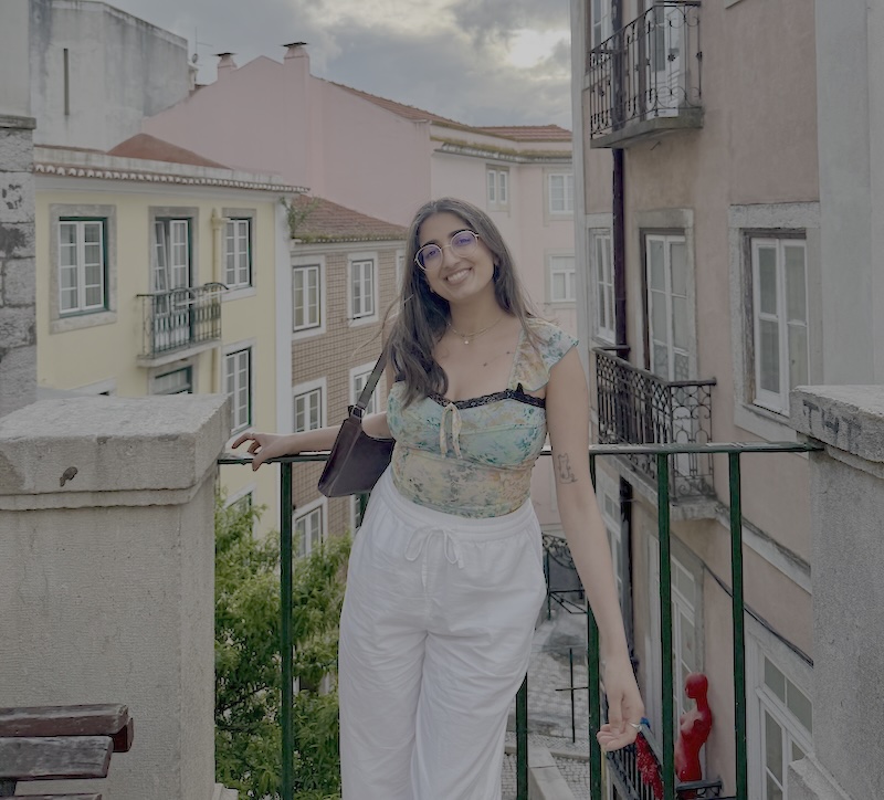 Mariya standing in front of a railing overlooking houses