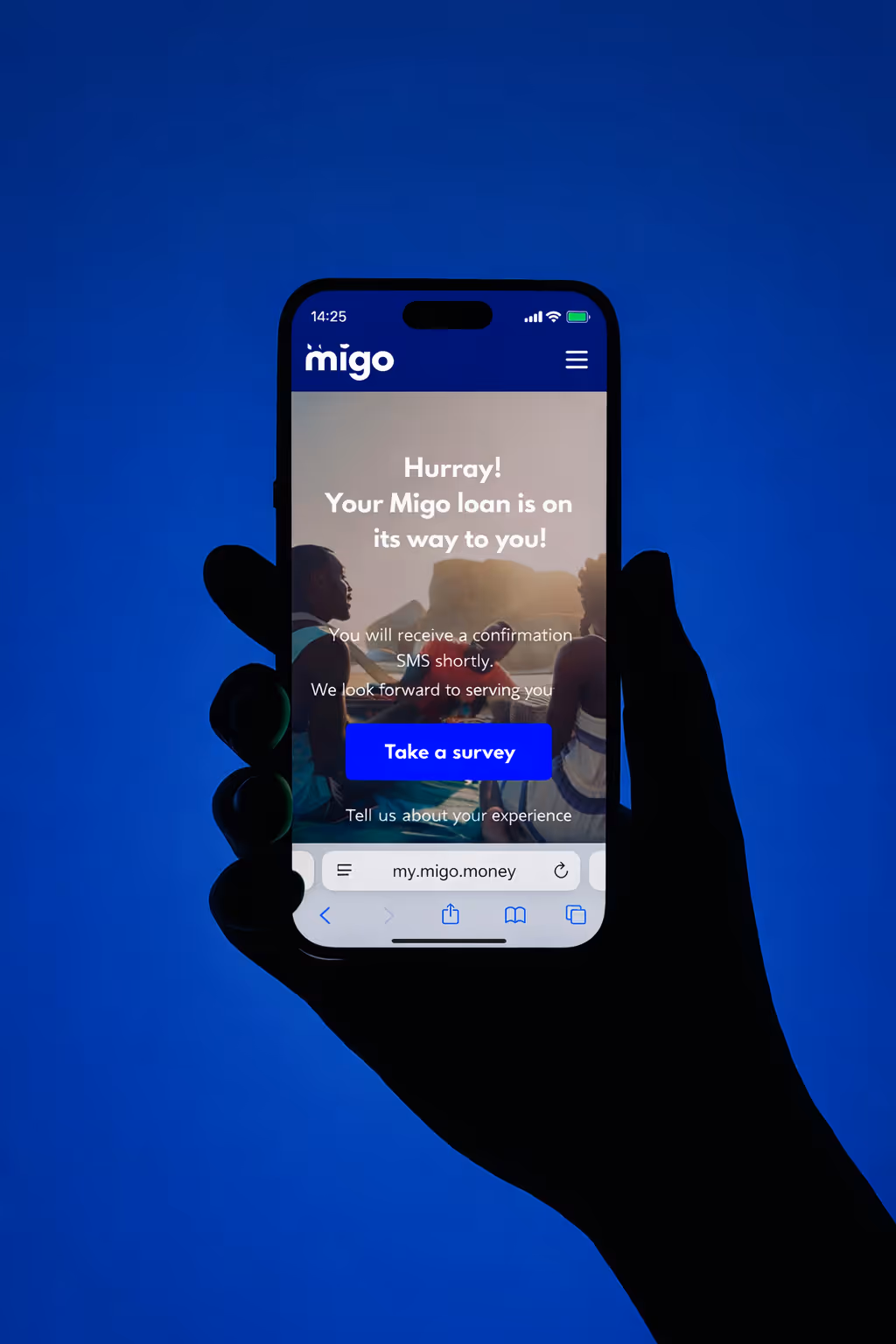 Hand holding phone displaying Migo app confirmation that loan is on its way, with a button to take a survey.
