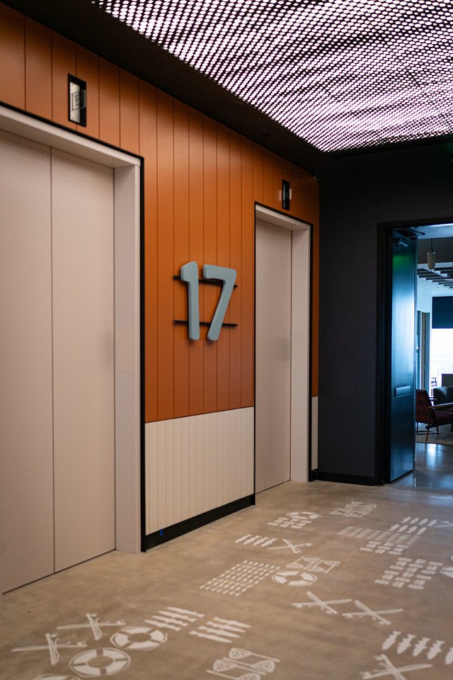 Elevator lobby floor identification numeral 17 on an orange paneled wall