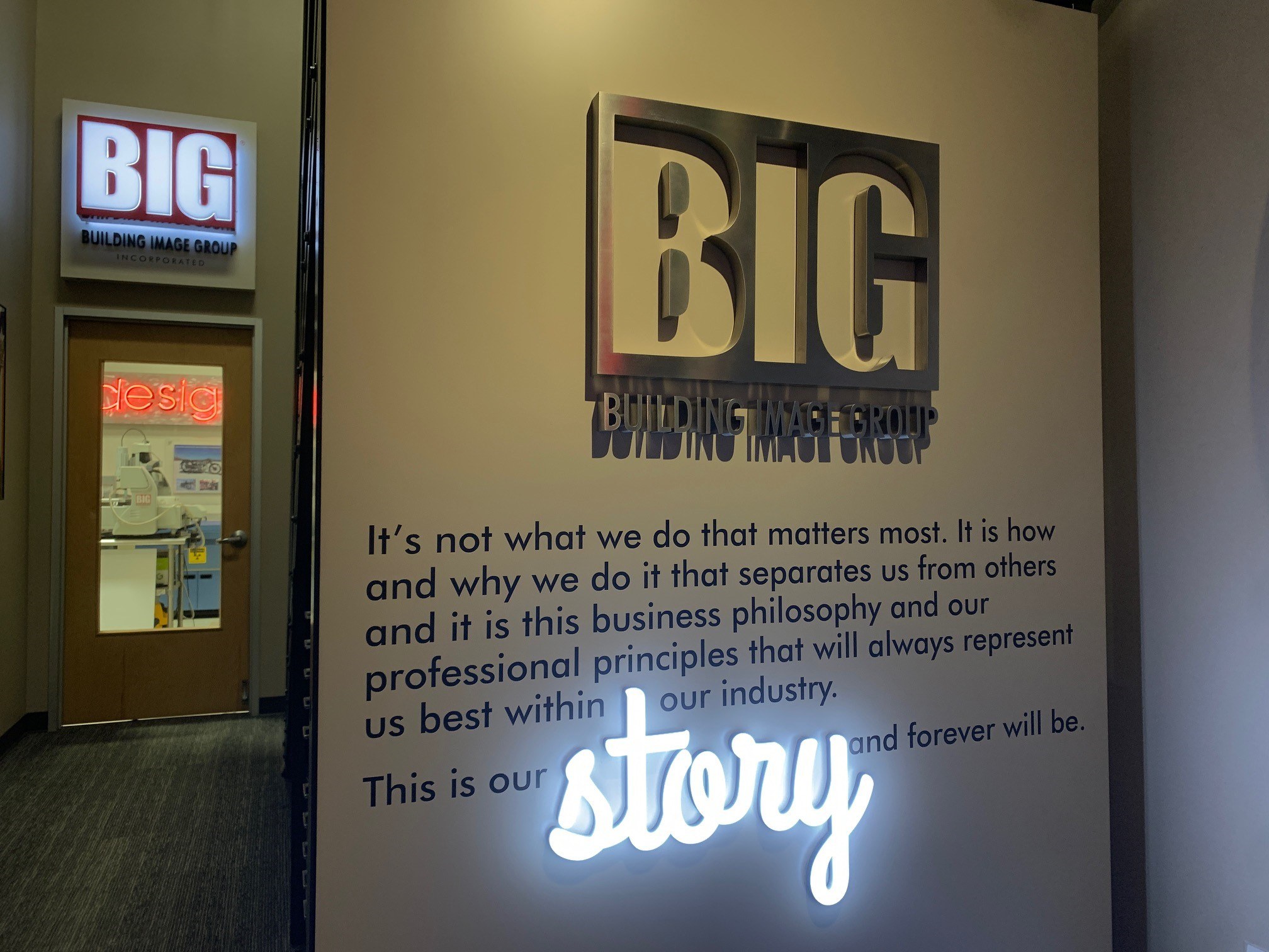 Illuminated dimensional BIG Building Image Group lobby sign with a backlit script sign reading story