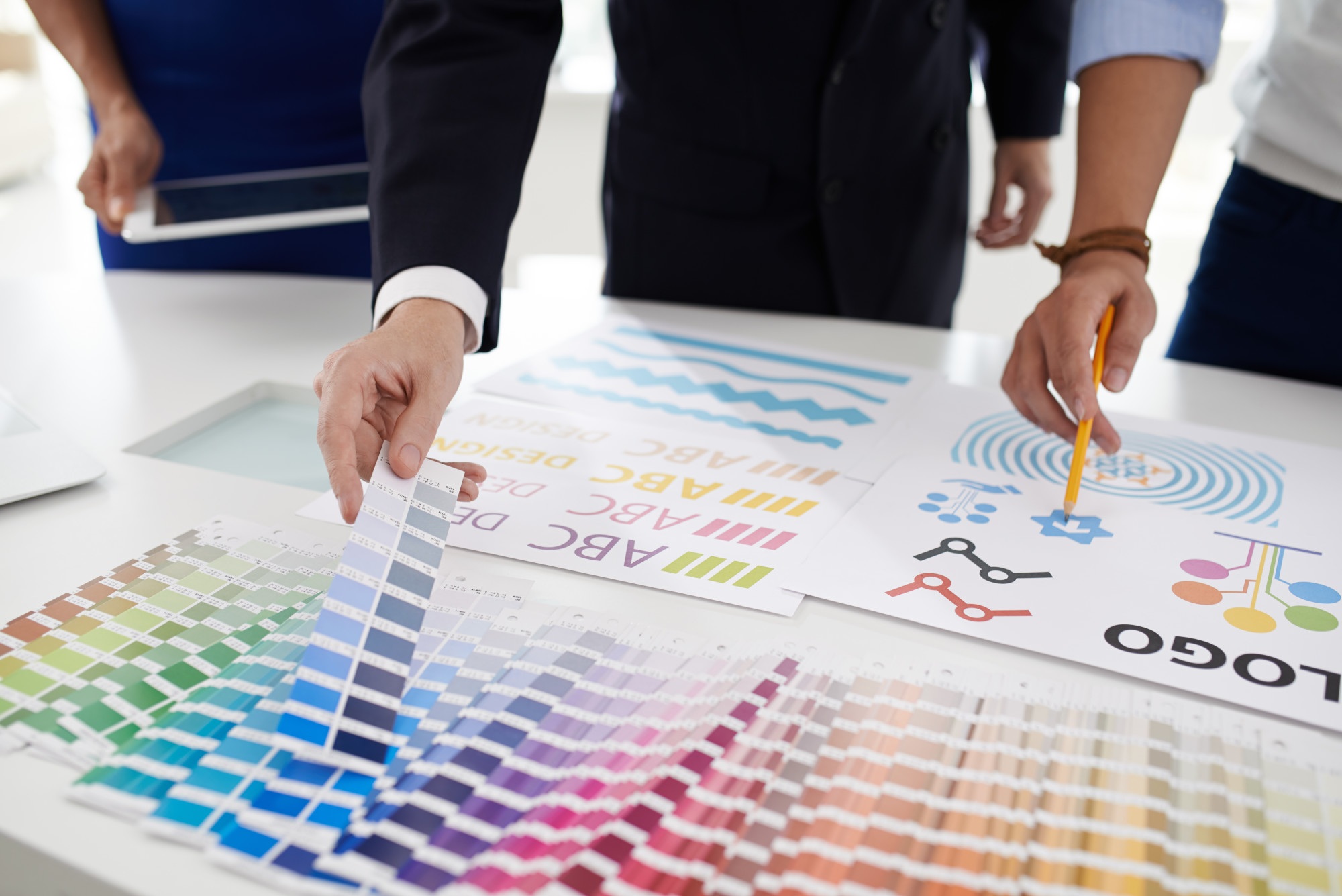 Designers reviewing Pantone color swatches and logo concept sheets on a table