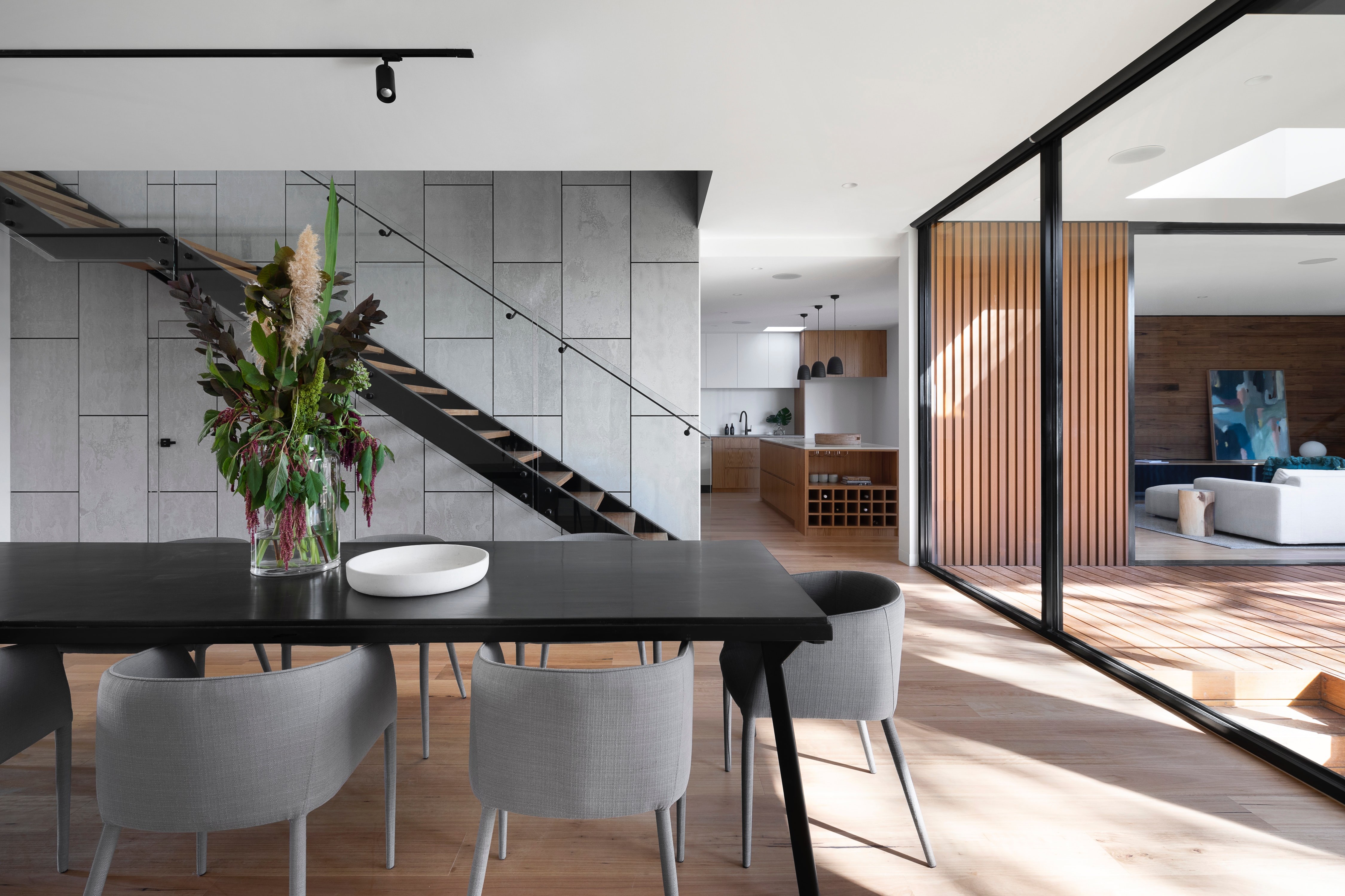 Modern open-concept interior with a floating staircase and glass doors opening to an outdoor deck