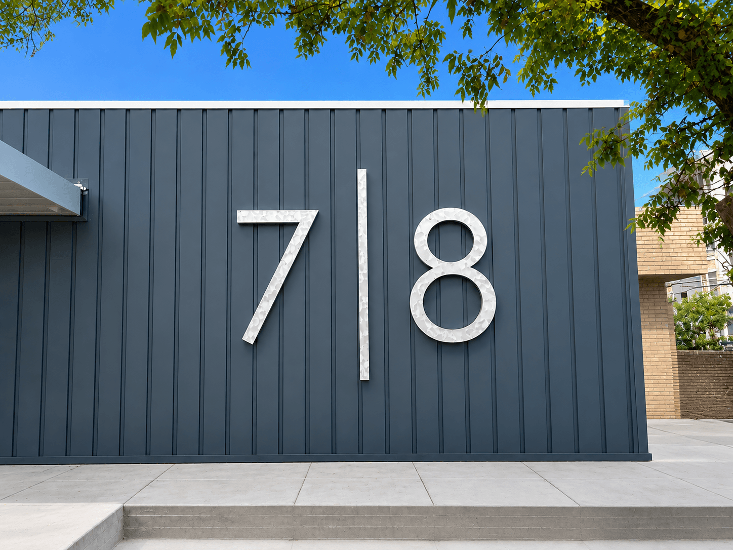 Brushed metal dimensional building numerals 7 and 8 on a dark blue fire station facade