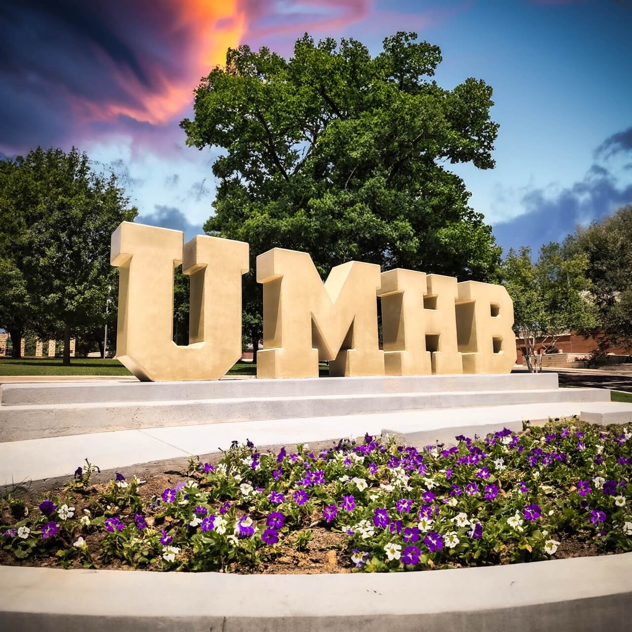 Large gold dimensional UMHB campus letters on a stepped concrete monument base