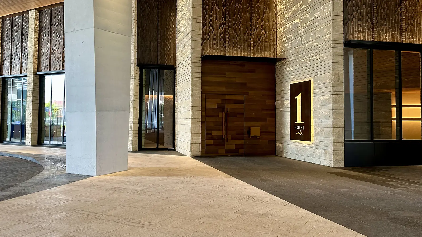 Backlit gold 1 Hotel entrance sign set into a textured stone hotel facade