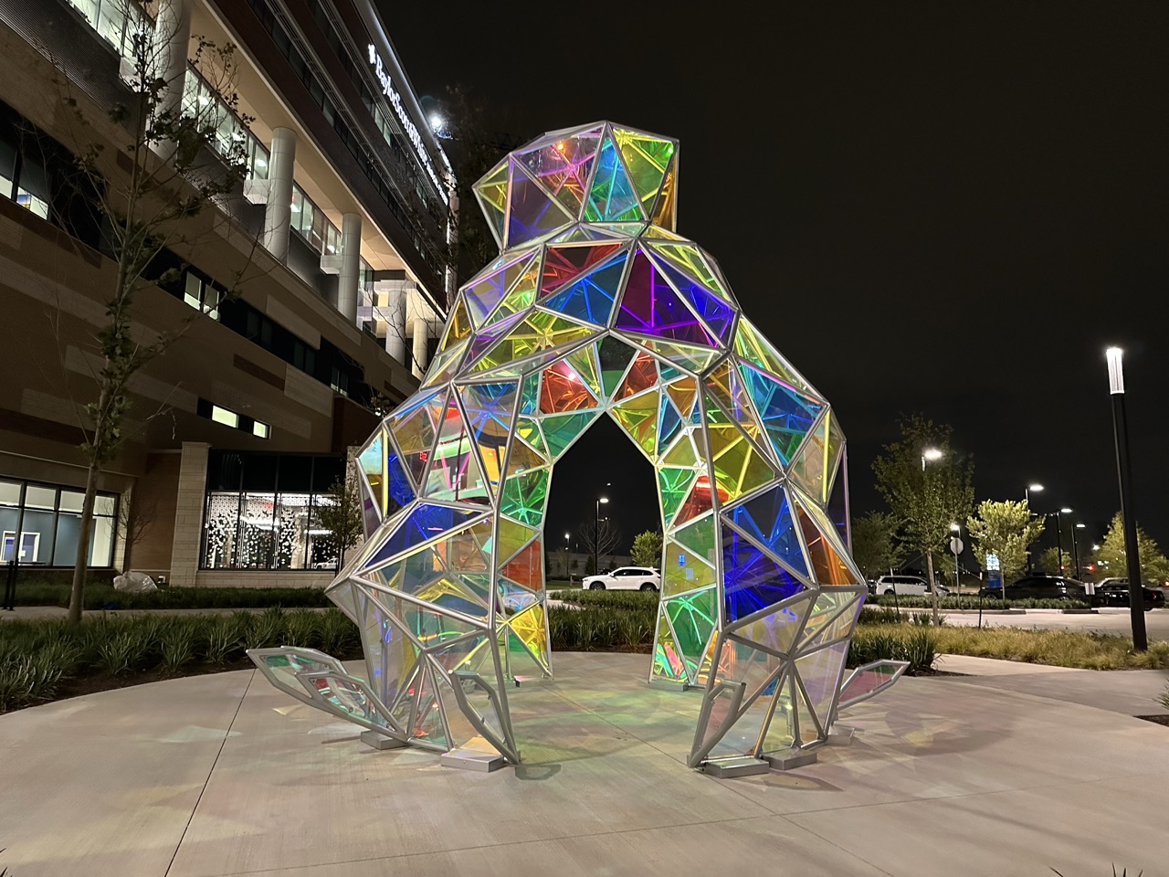 Illuminated faceted glass archway sculpture at the Baylor Scott and White campus entrance at night