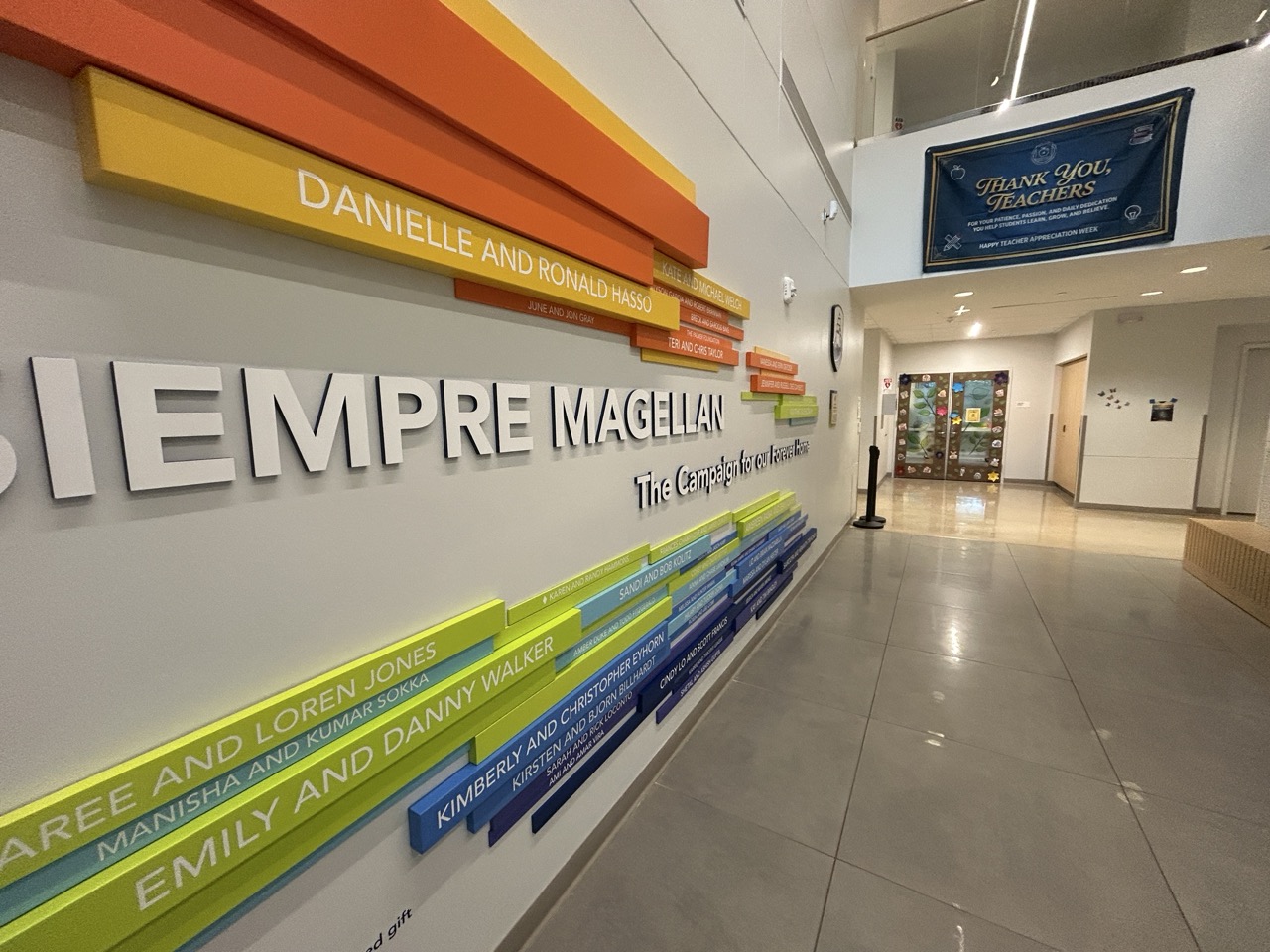 Colorful staggered donor recognition wall reading Siempre Magellan with named plaques