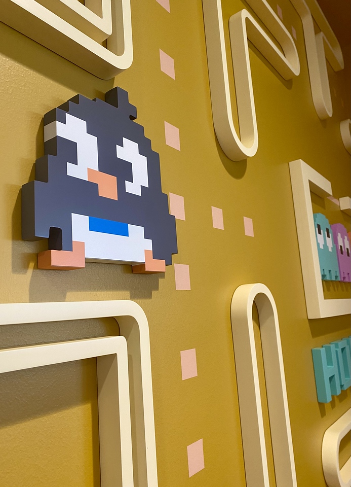 Dimensional pixel-art penguin and maze wall graphics in a playful office environmental design