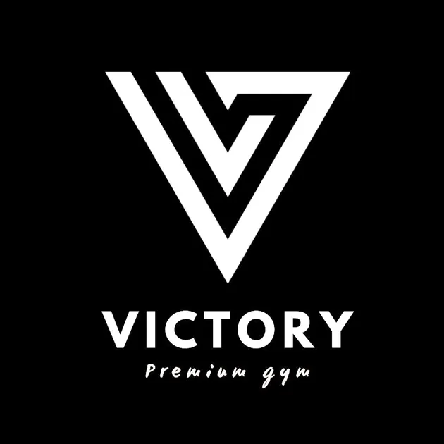 Valkoinen, tyylitelty V-kirjainlogo mustalla taustalla, alla teksti "VICTORY Premium gym".