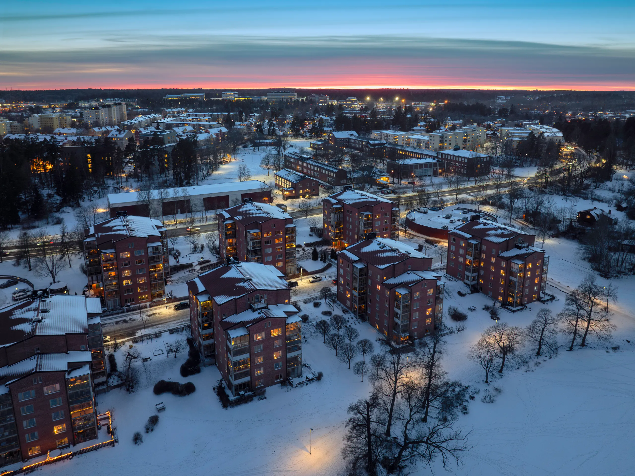 Kerrostaloalue lumisessa kaupungissa talvi-illan valaistuksessa