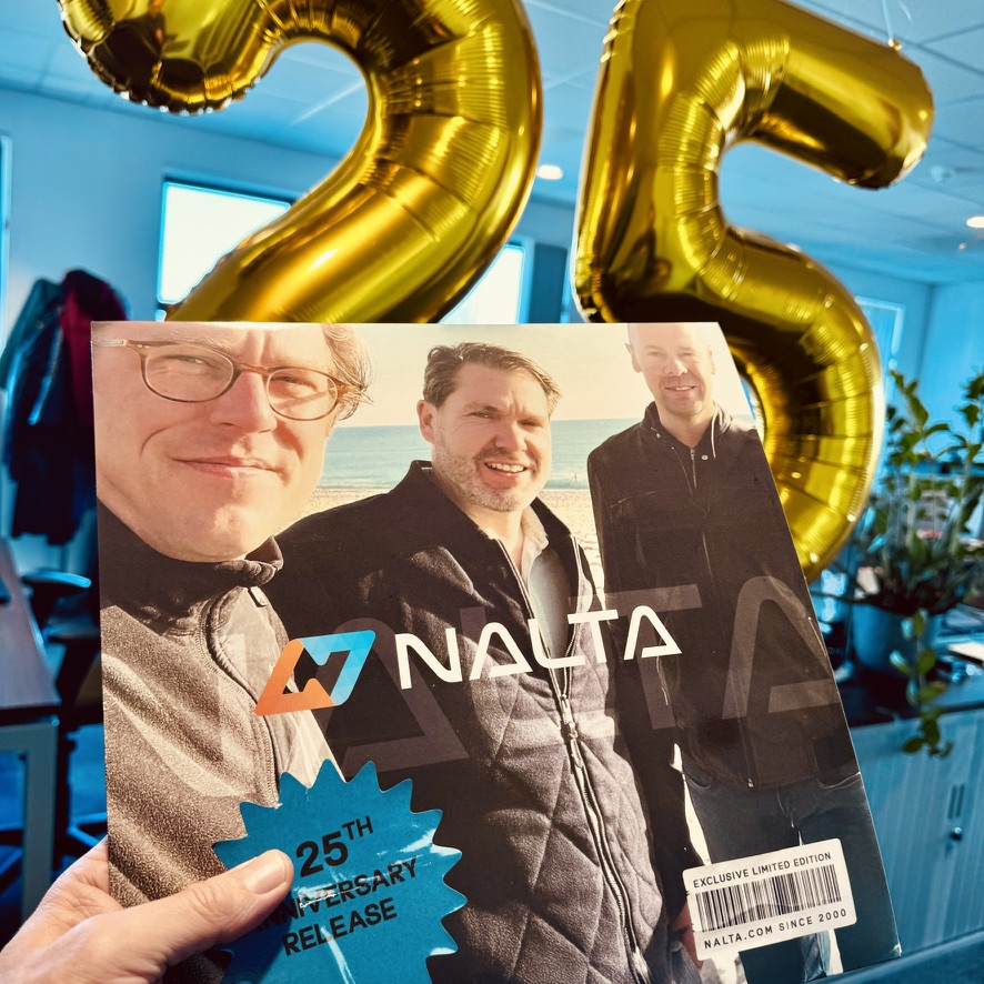 Hand houdt Nalata 25-jarig jubileumeditie met portret van drie mannen en gouden ballonnen '25'.