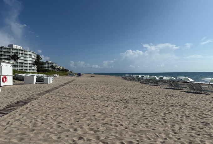 Sandy beach in front of Four Seasons Resort Palm Beach with gentle waves and clear blue sky