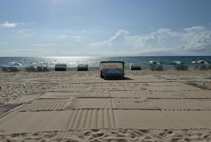 Well-kept sandy beach at Four Seasons Resort Palm Beach with clear blue water and neatly arranged loungers
