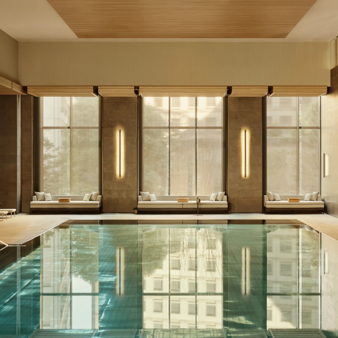 Janu Tokyo indoor pool with warm wood interiors and large city-facing windows.