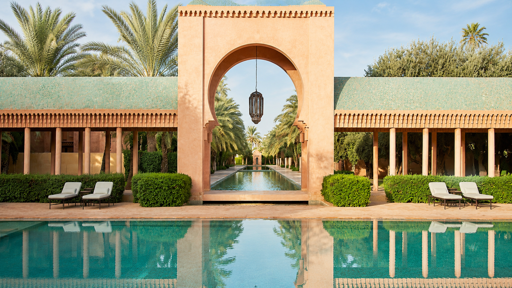 Sunlit pool courtyard at Aman Marrakech with Moroccan architecture, palm trees, and reflecting water.