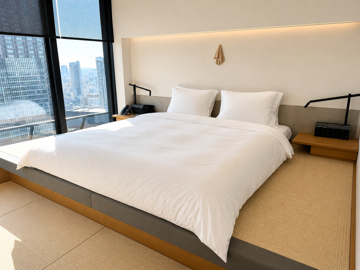 Bedroom in the Four Seasons Osaka Tatami Suite featuring a low platform bed, traditional tatami flooring, floor-to-ceiling windows, and panoramic Osaka city views.
