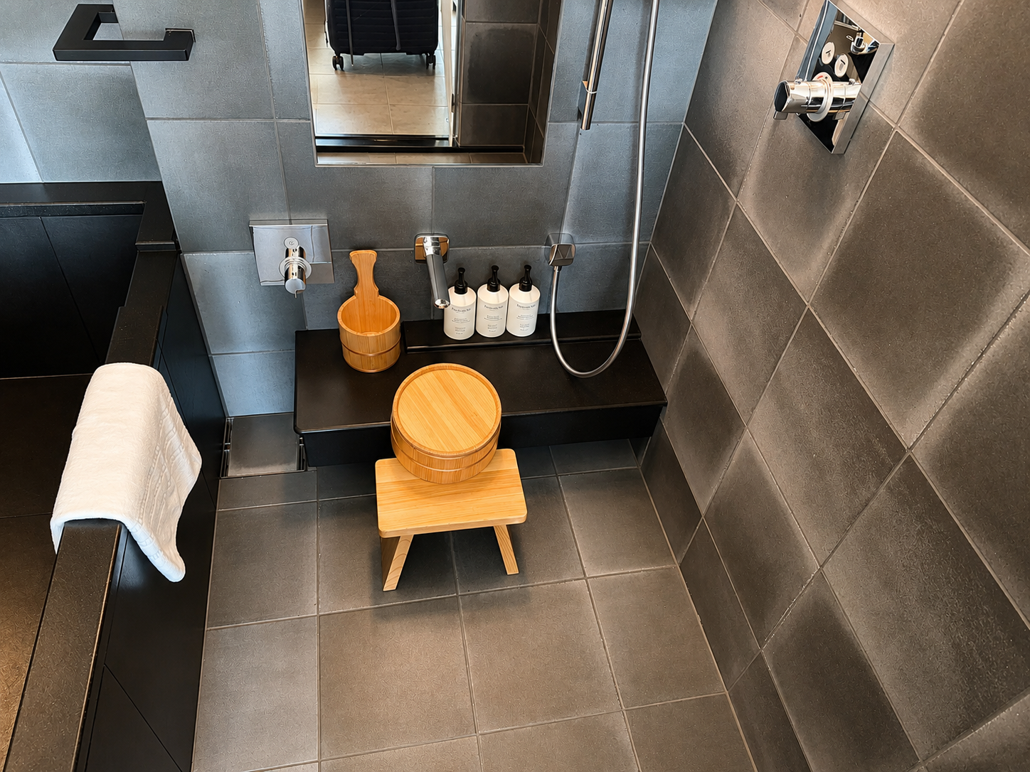 Traditional Japanese bathing area in the Tatami Suite at Four Seasons Osaka featuring a wooden soaking bucket, shower stool, and deep bathtub.