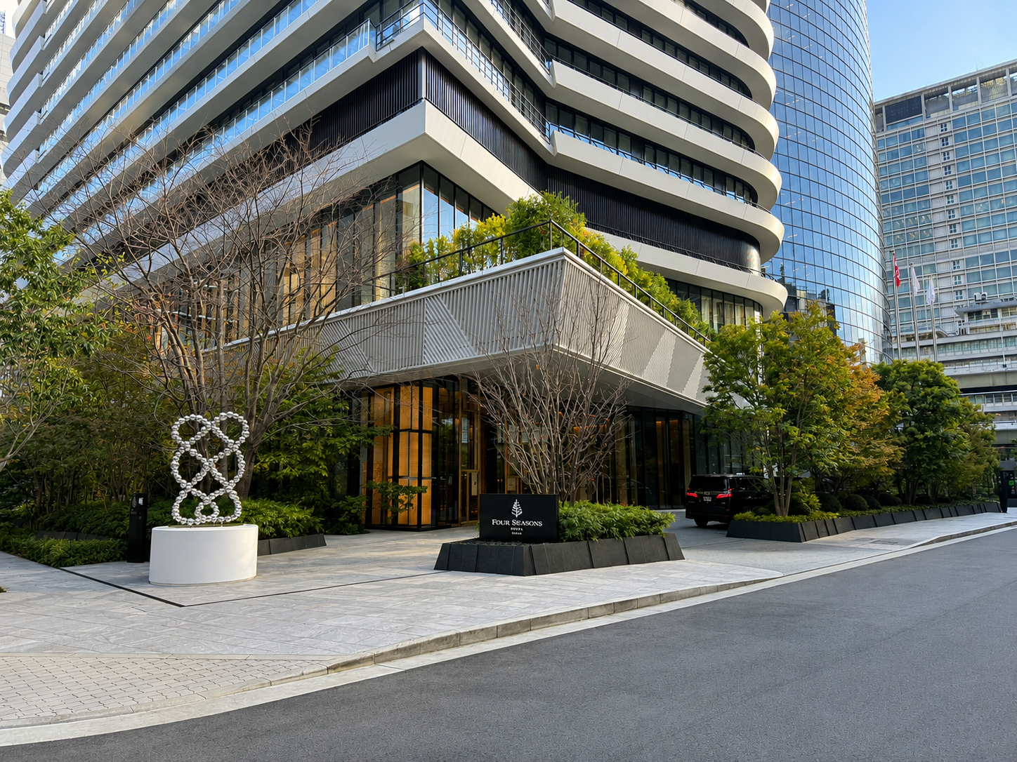 Exterior entrance of Four Seasons Hotel Osaka at One Dojima tower with landscaped gardens and contemporary architecture in central Osaka.