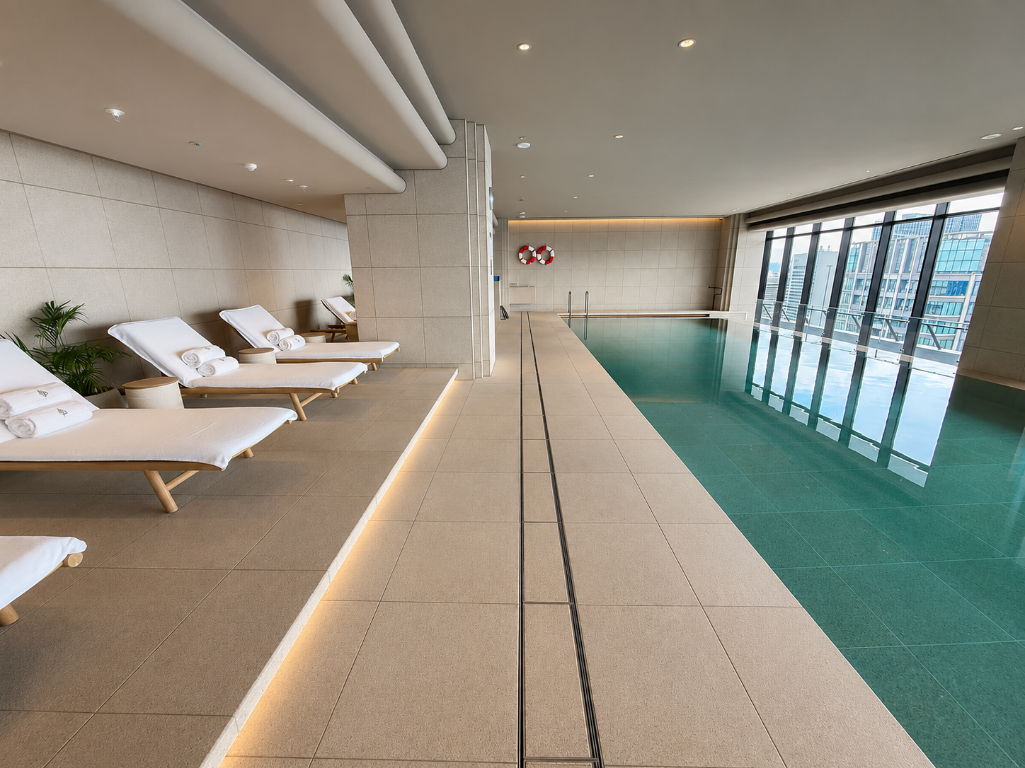Heated indoor swimming pool with loungers and city views at Four Seasons Hotel Osaka.