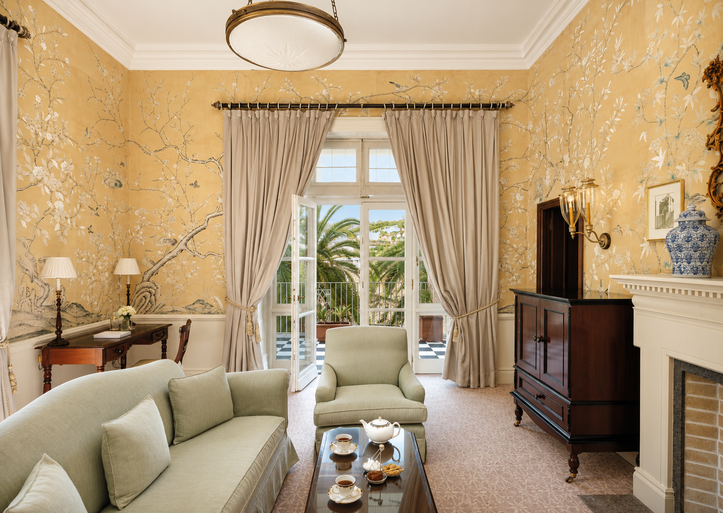 Living room of the Churchill Suite at Reid’s Palace, a Belmond Hotel in Madeira, with hand-painted walls, classic furnishings and terrace access.