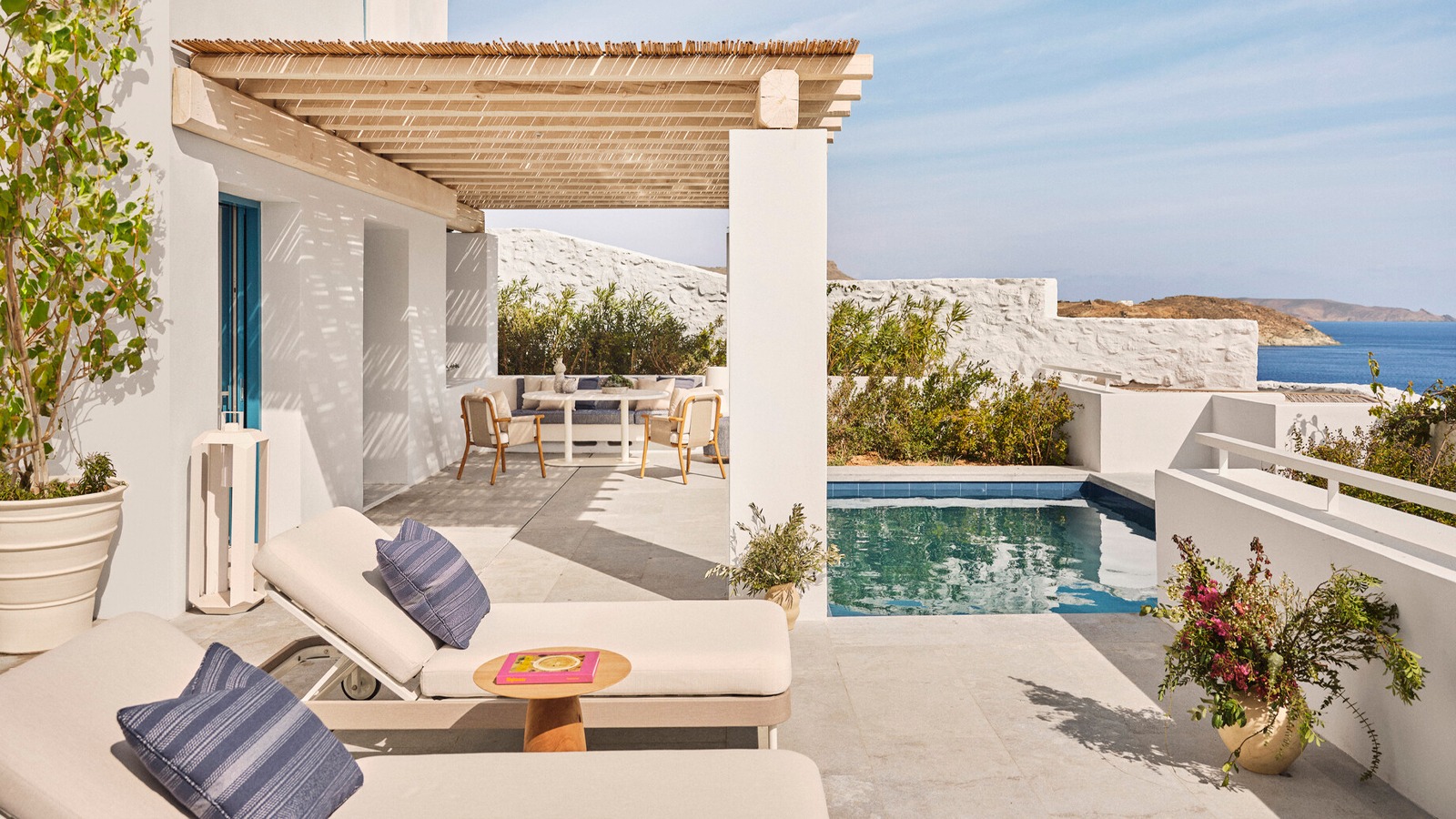 Private pool terrace at Four Seasons Resort Mykonos with sun loungers, outdoor dining and views of the Aegean Sea.