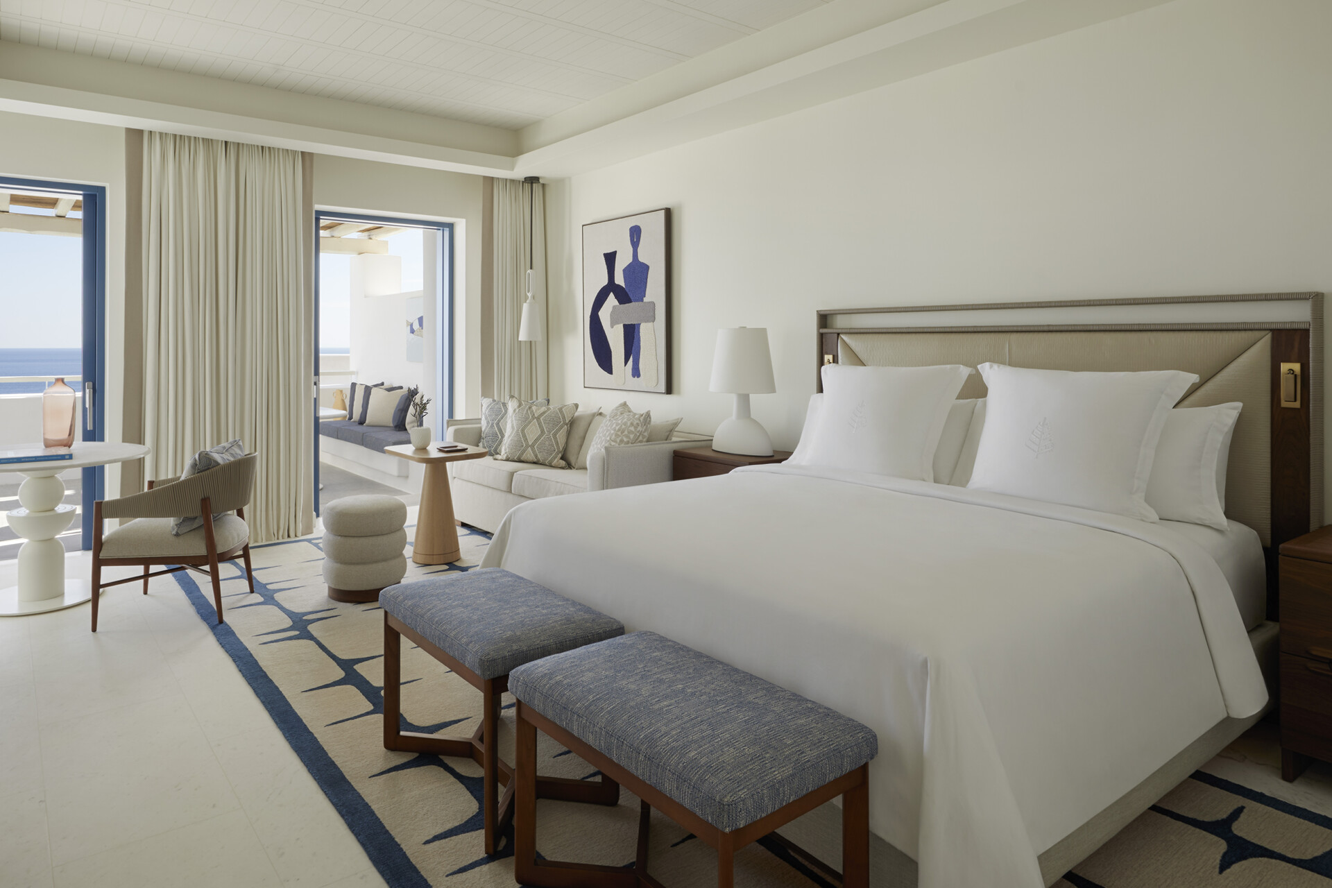 Premier sea view guest room at Four Seasons Resort Mykonos with king bed, sitting area and private terrace.