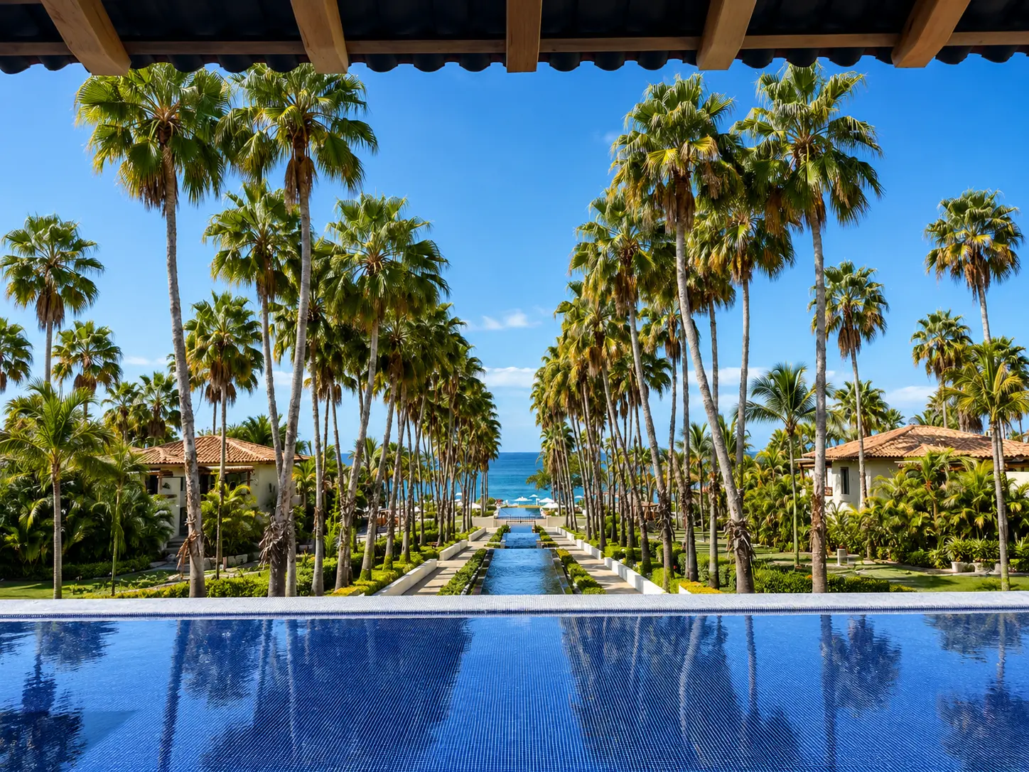 View from the lobby at The St. Regis Punta Mita overlooking palm trees, reflecting pools and the Pacific Ocean.