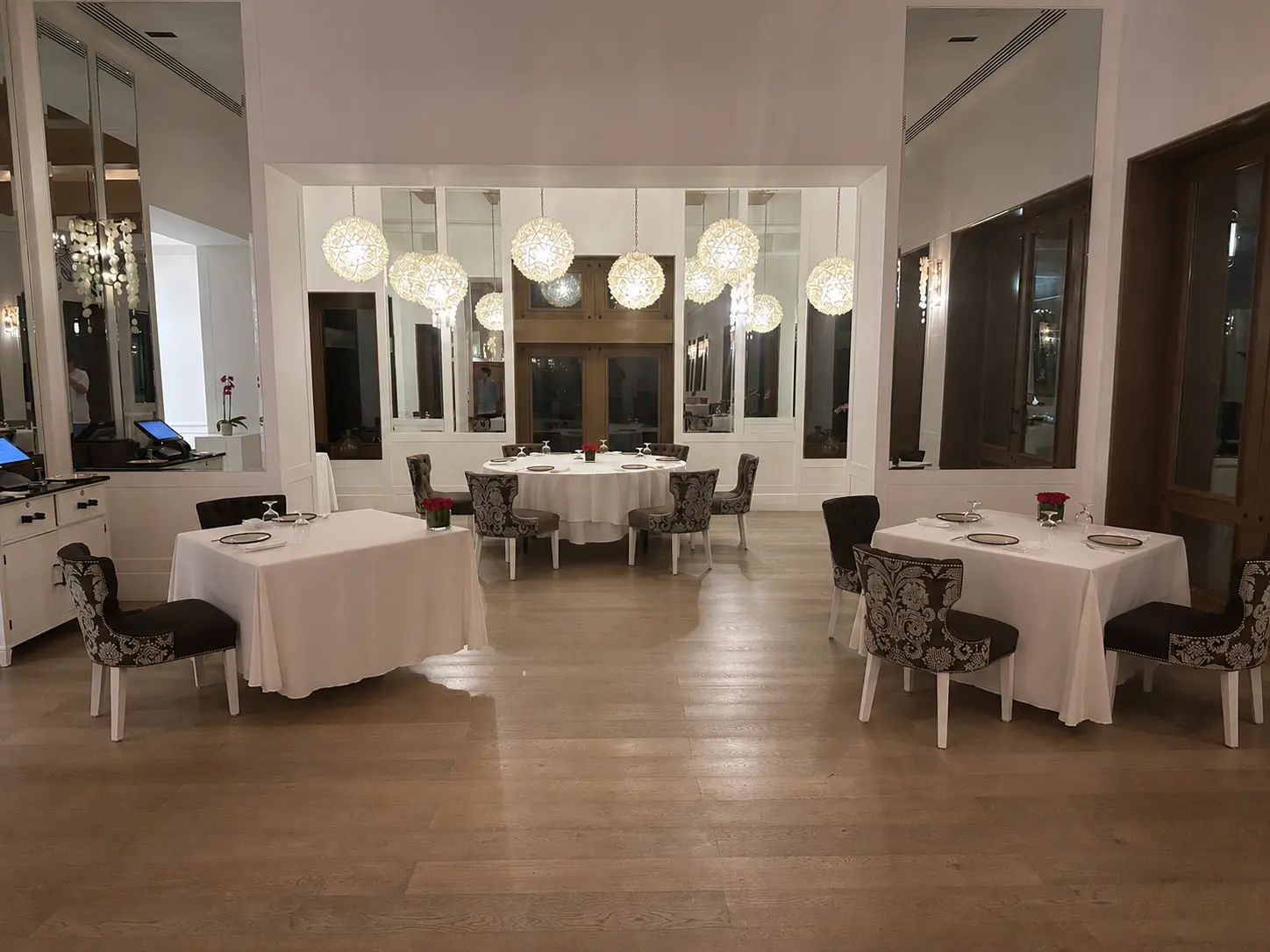 Dining room at Carolina restaurant at The St. Regis Punta Mita with white tablecloths, patterned chairs and pendant lighting.