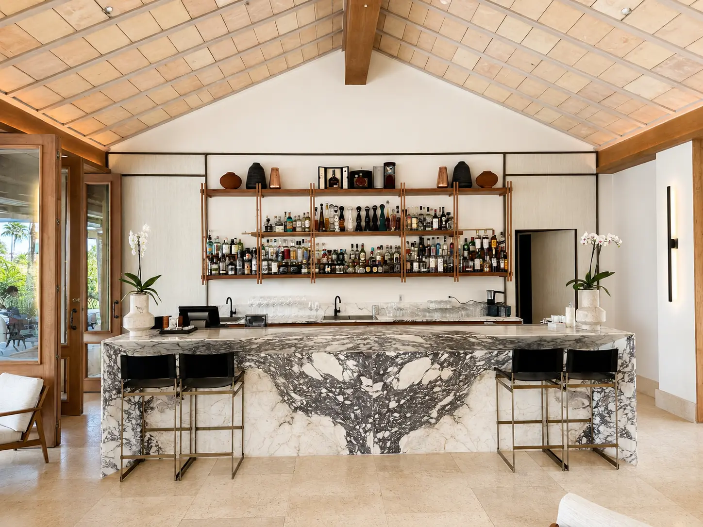 Lobby bar at The St. Regis Punta Mita with a marble counter, vaulted ceiling and open shelves of spirits.