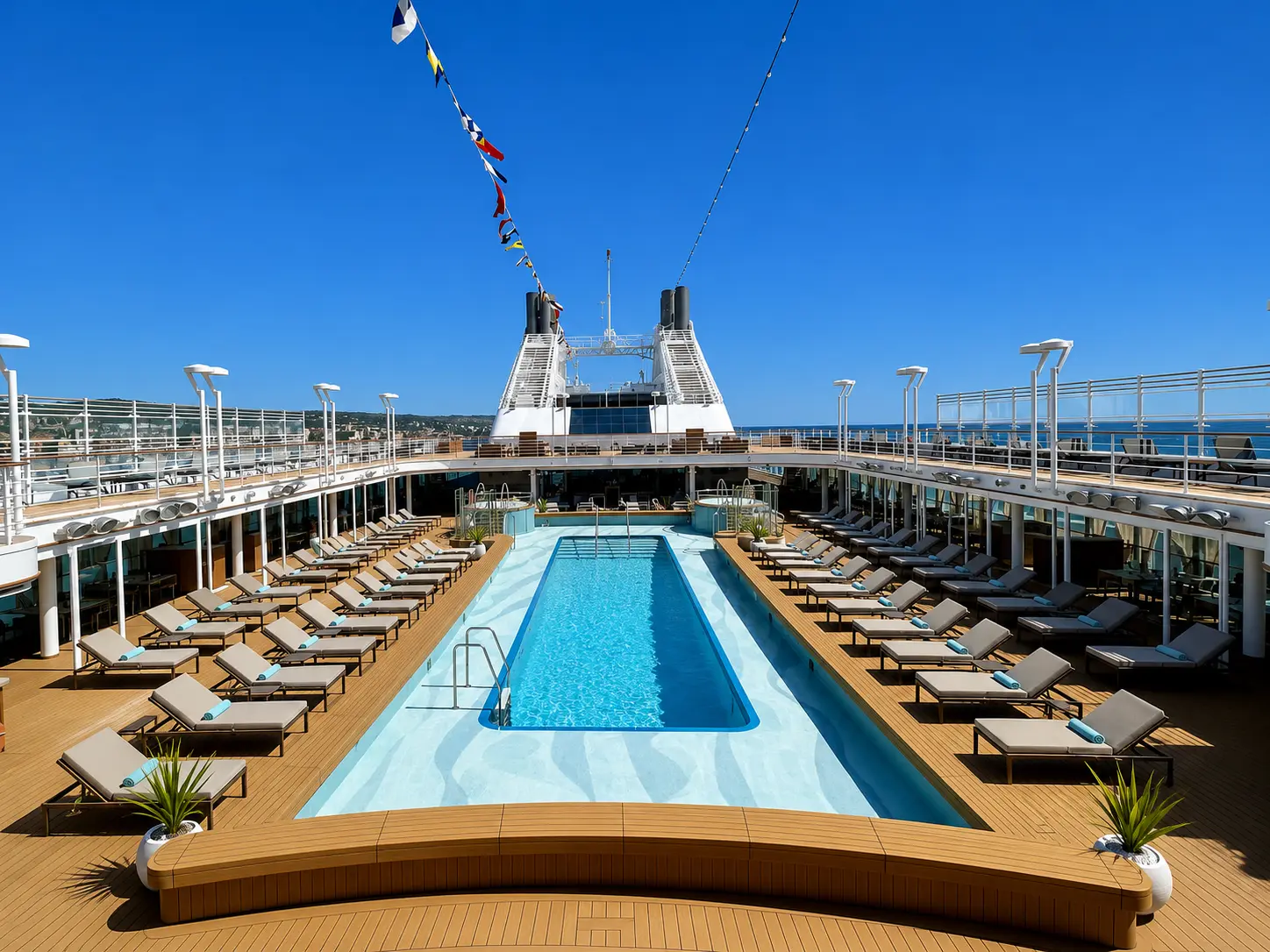 The pool deck aboard Silversea Silver Dawn with sun loungers, teak decking and ocean views.