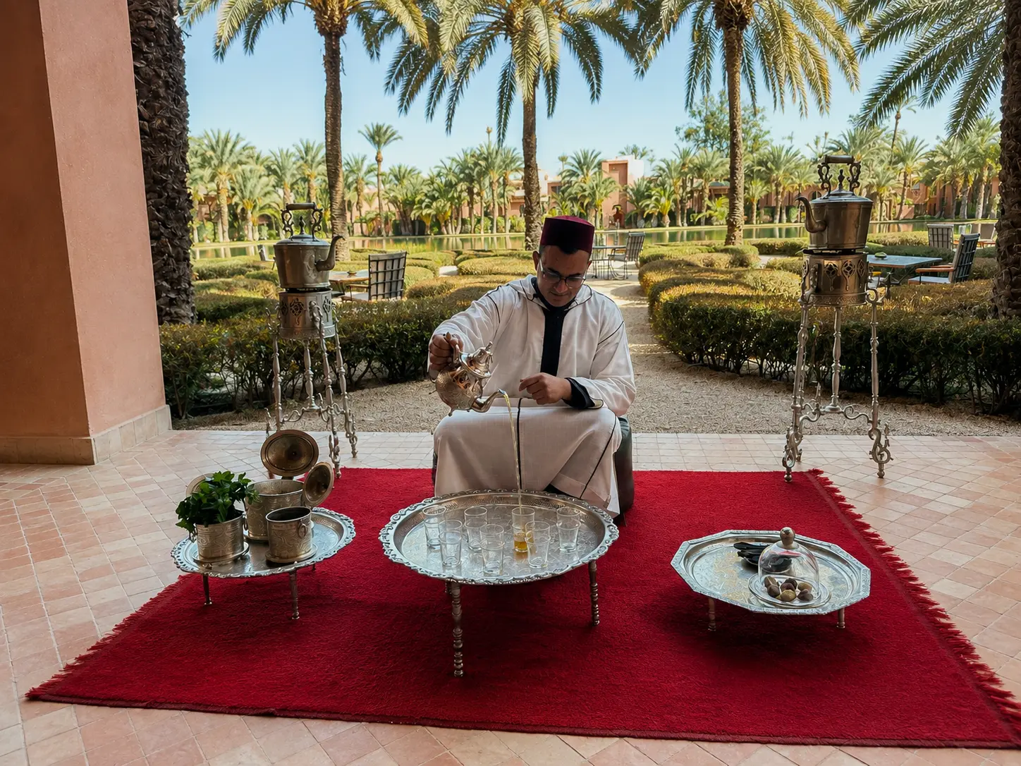 Traditional Moroccan tea ceremony at Amanjena Marrakech, with a host pouring mint tea in the palm-lined courtyard.