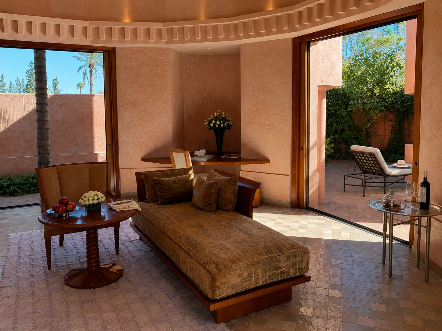 Living area inside a Deluxe Pavilion at Amanjena Marrakech with a daybed, fireplace, writing desk, and private courtyard.