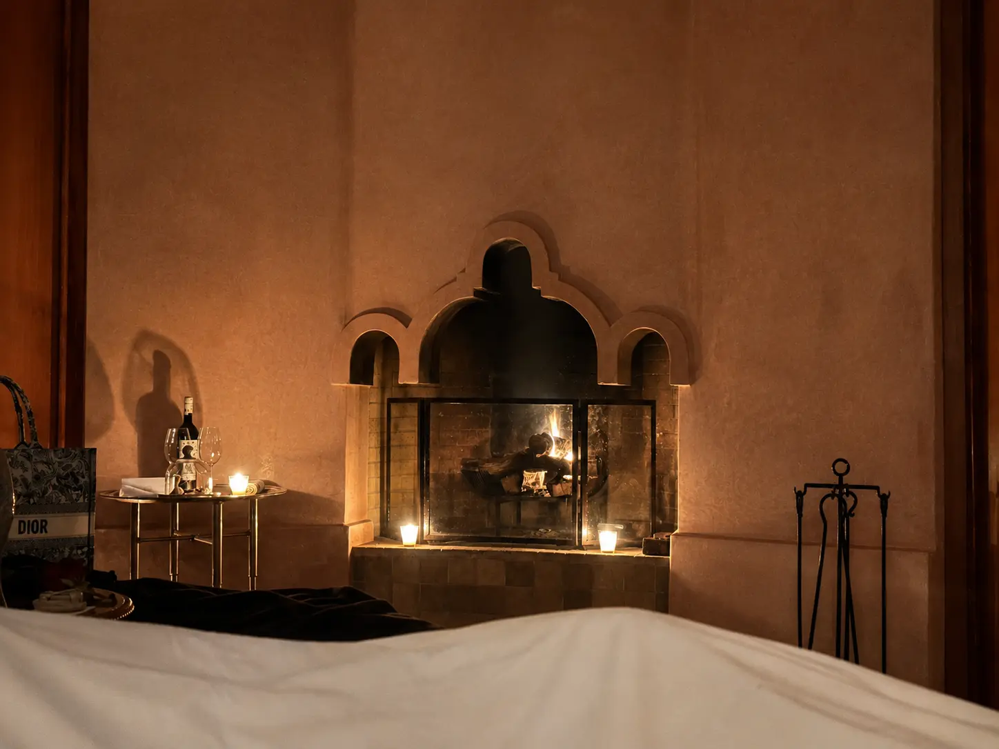 View from bed inside a Deluxe Pavilion at Amanjena Marrakech with the fireplace lit in the evening.