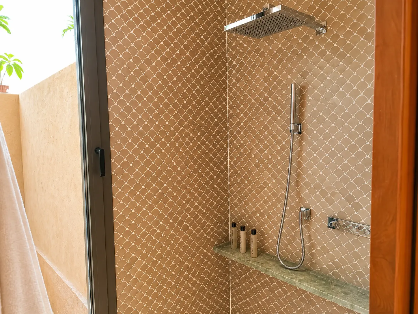 Walk-in rainfall shower inside a Deluxe Pavilion at Amanjena Marrakech with scalloped Moroccan tiles and Amanjena toiletries.