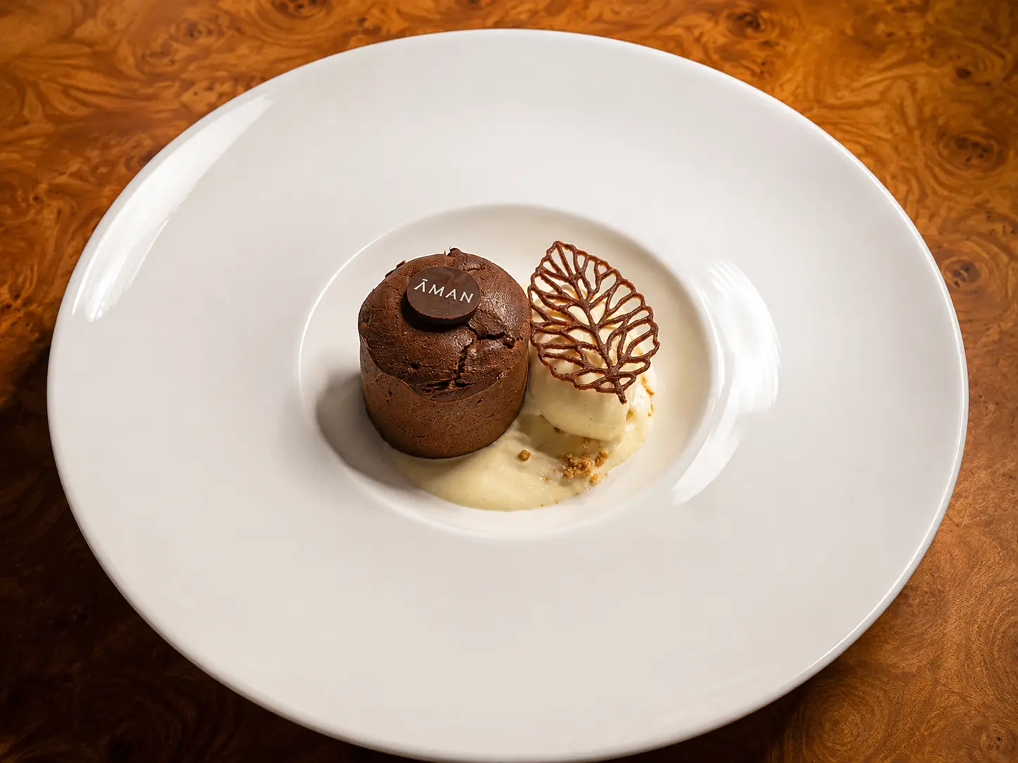 Signature chocolate dessert served at Nama restaurant at Amanjena in Marrakech, presented with vanilla ice cream and an Aman chocolate medallion.