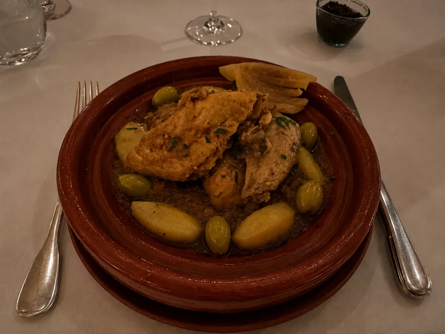 Traditional preserved lemon chicken tagine served at The Moroccan Restaurant at Amanjena in Marrakech with olives and potatoes in a classic clay tagine.