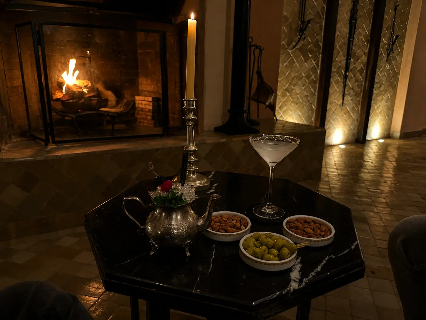 Evening cocktails beside the fireplace at Amanjena's bar in Marrakech, with candlelight, Moroccan décor, olives, and roasted almonds.