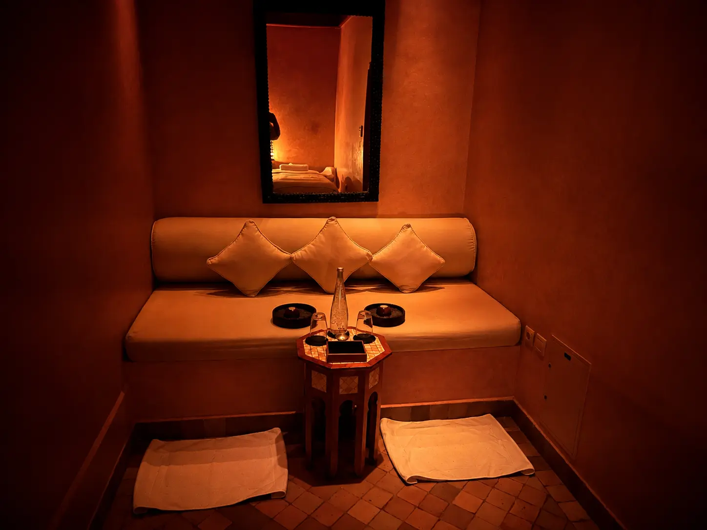 Relaxation room at the Aman Spa at Amanjena in Marrakech, featuring warm ambient lighting, a built-in daybed, traditional Moroccan architecture, and a tranquil space for guests to unwind before or after treatments.