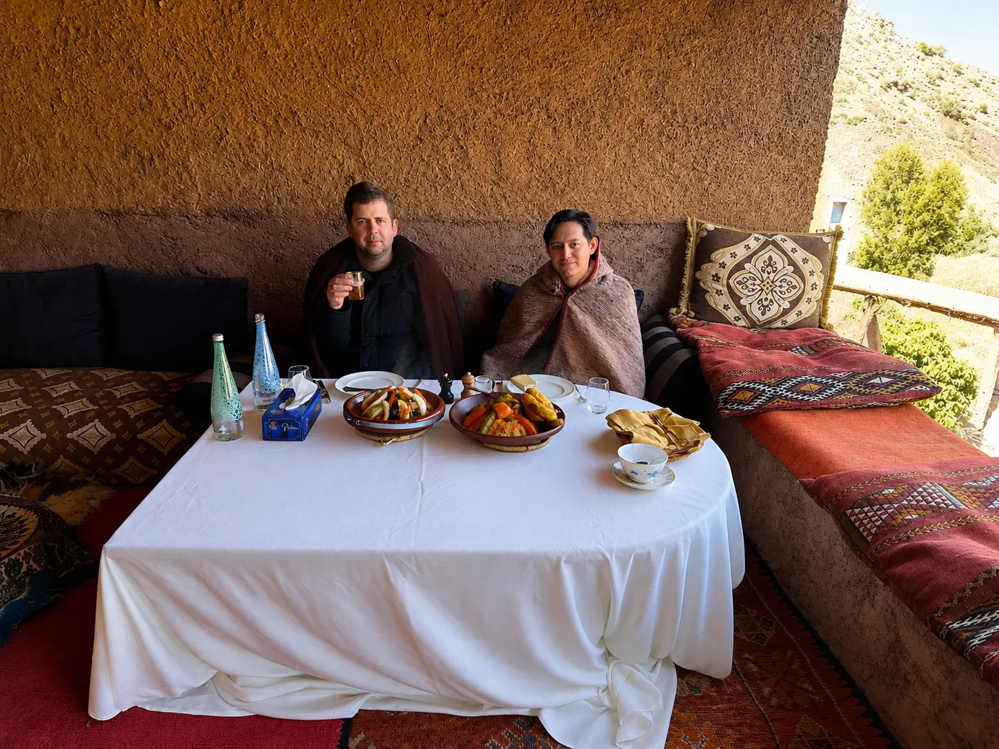 Traditional Berber lunch in the Atlas Mountains near Marrakech during an Amanjena private excursion, featuring authentic Moroccan tagines served in a rustic mountain setting.