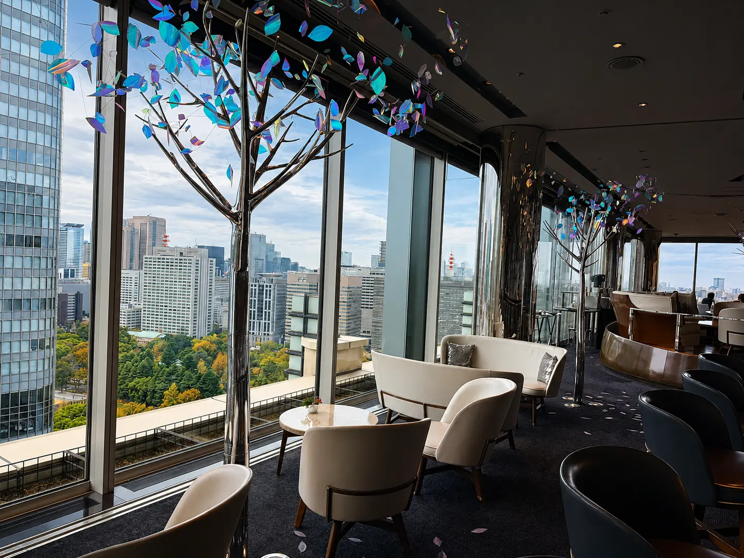 The Bar at The Peninsula Tokyo with floor-to-ceiling windows, sculptural tree installations and views across central Tokyo.