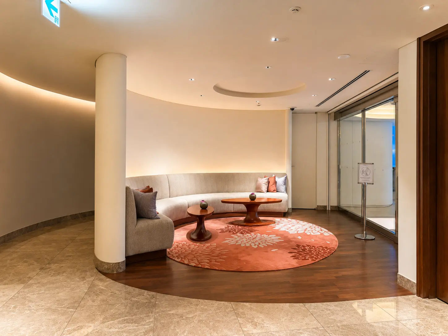 Spa lobby and relaxation area at The Peninsula Tokyo with curved seating, warm lighting and wood flooring.