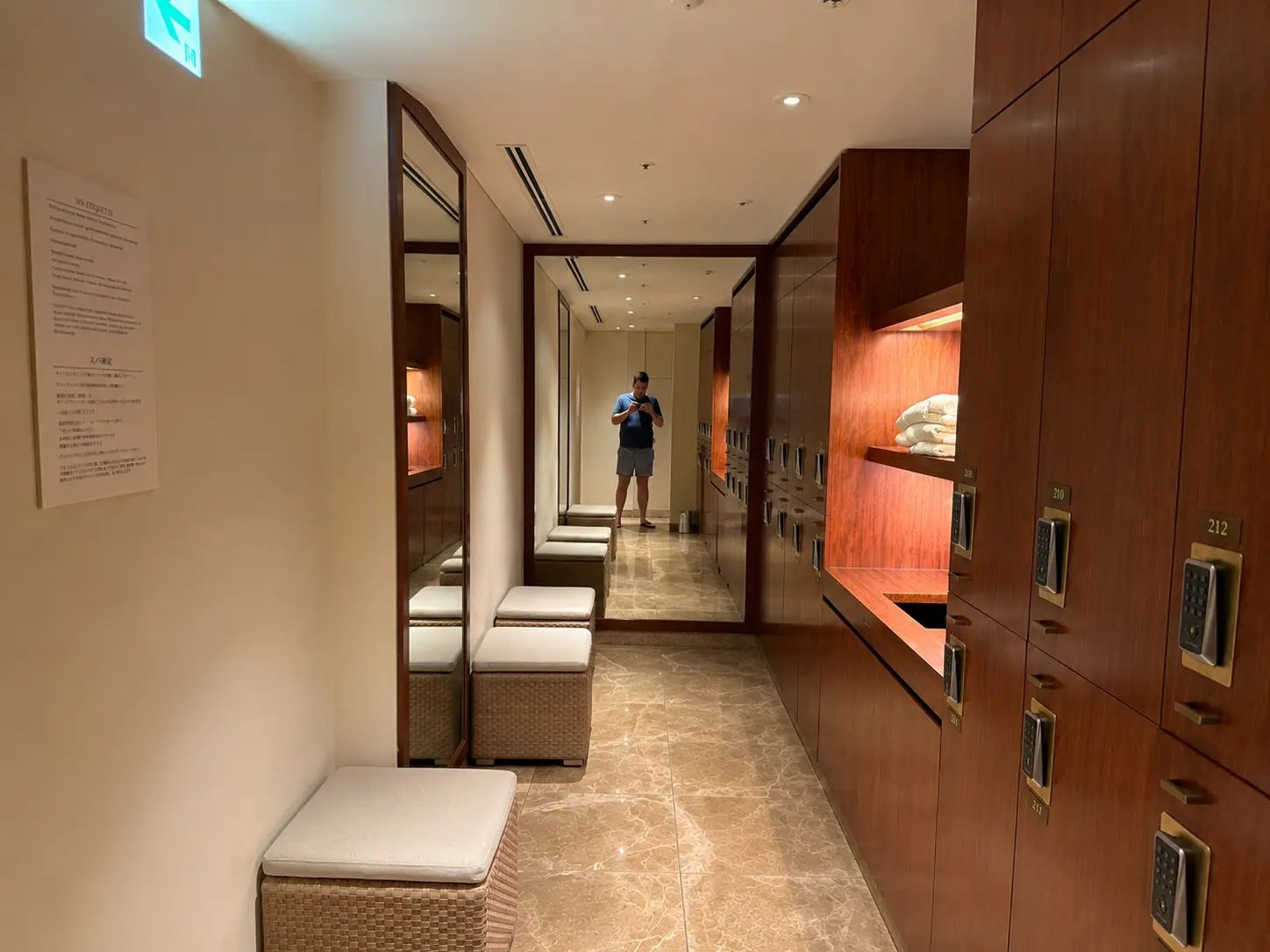 Spa locker room at The Peninsula Tokyo with wood lockers, marble flooring, changing benches and mirrors.