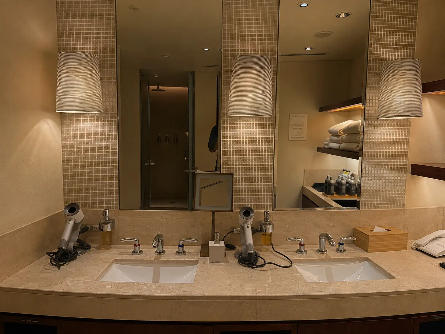 Changing room vanity at The Peninsula Spa Tokyo with marble sinks, mirrors, hair dryers and guest amenities.