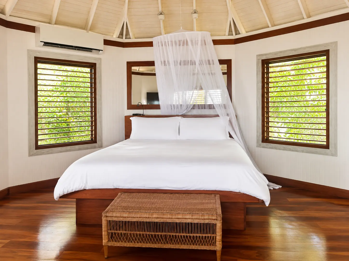 One Bedroom Beach Hut at GoldenEye Jamaica with king bed, mosquito netting, wooden floors and louvered windows overlooking tropical gardens.