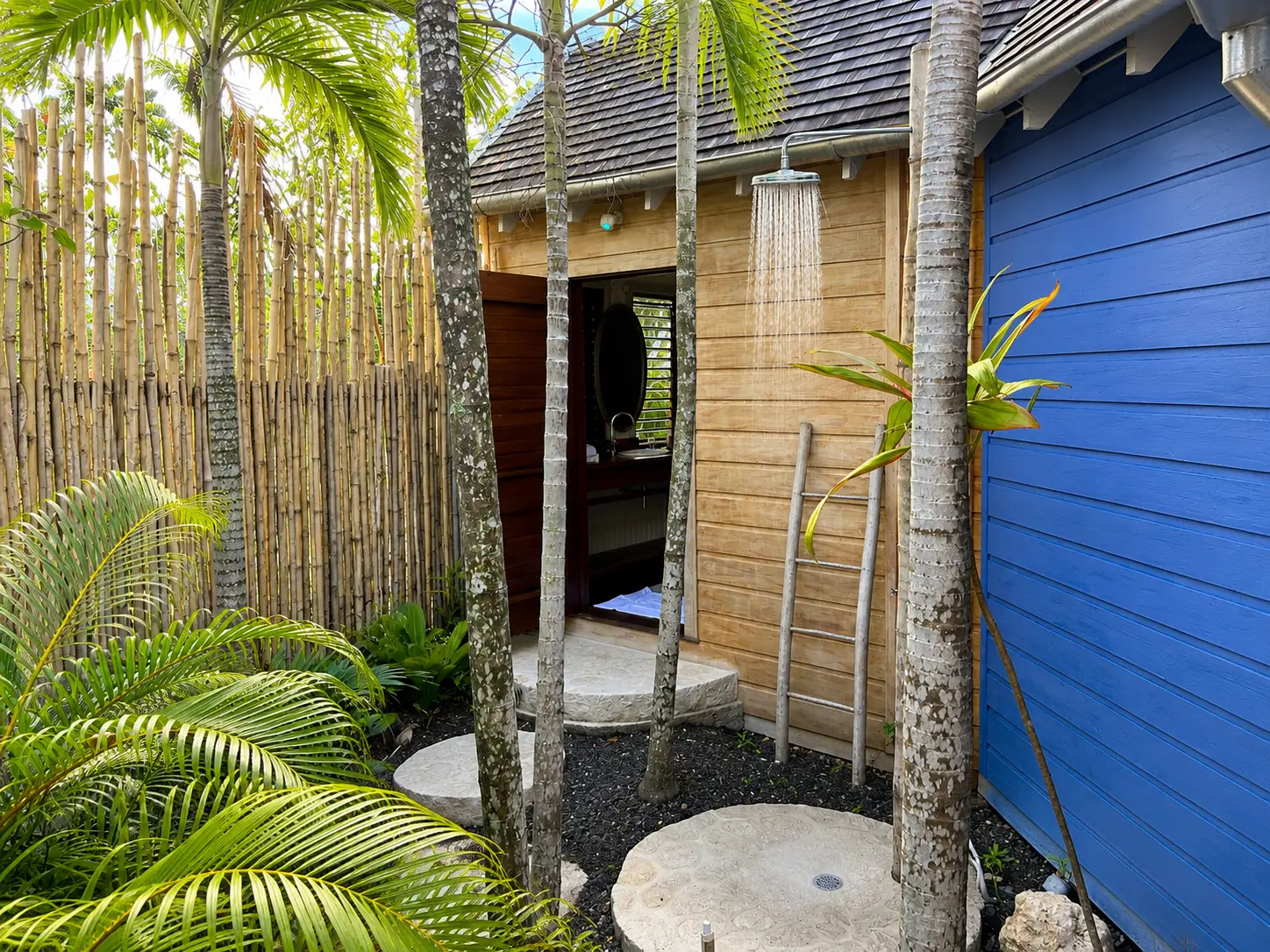 Private outdoor shower at a One Bedroom Beach Hut at GoldenEye Jamaica, enclosed by bamboo and tropical gardens.
