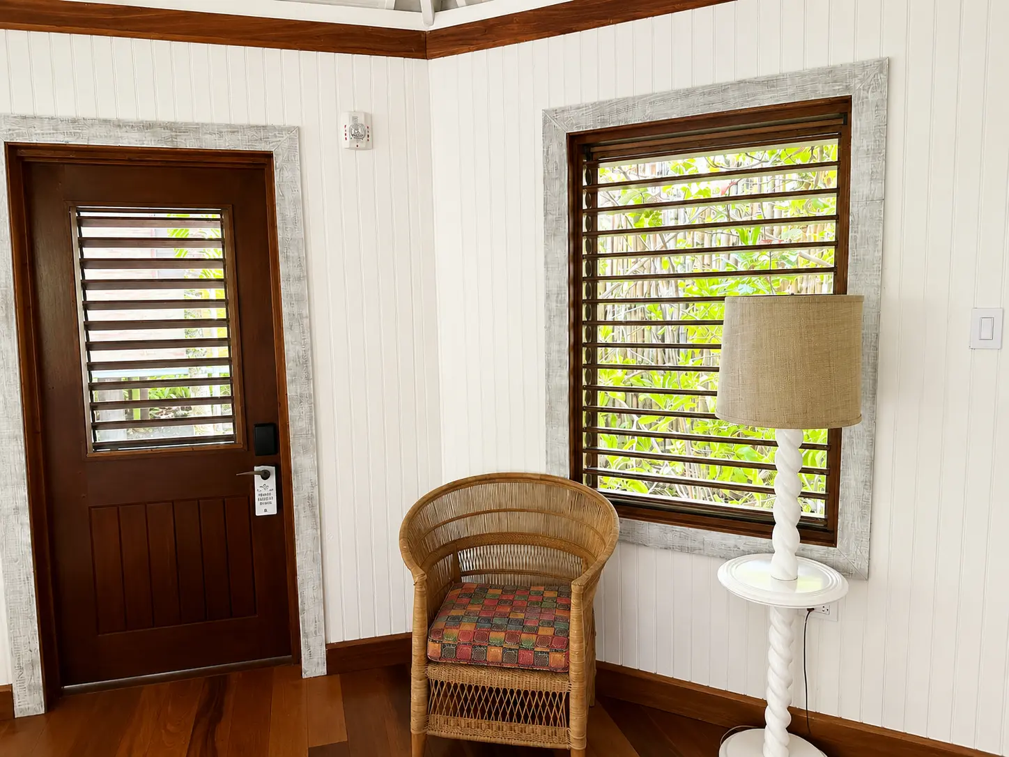 Interior details of a One Bedroom Beach Hut at GoldenEye Jamaica with wooden shutters, wicker chair and tropical garden views.