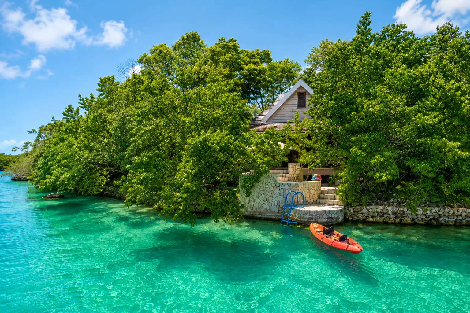 Lagoon Villa at GoldenEye Jamaica with private steps leading directly into the turquoise lagoon and a kayak on the water.