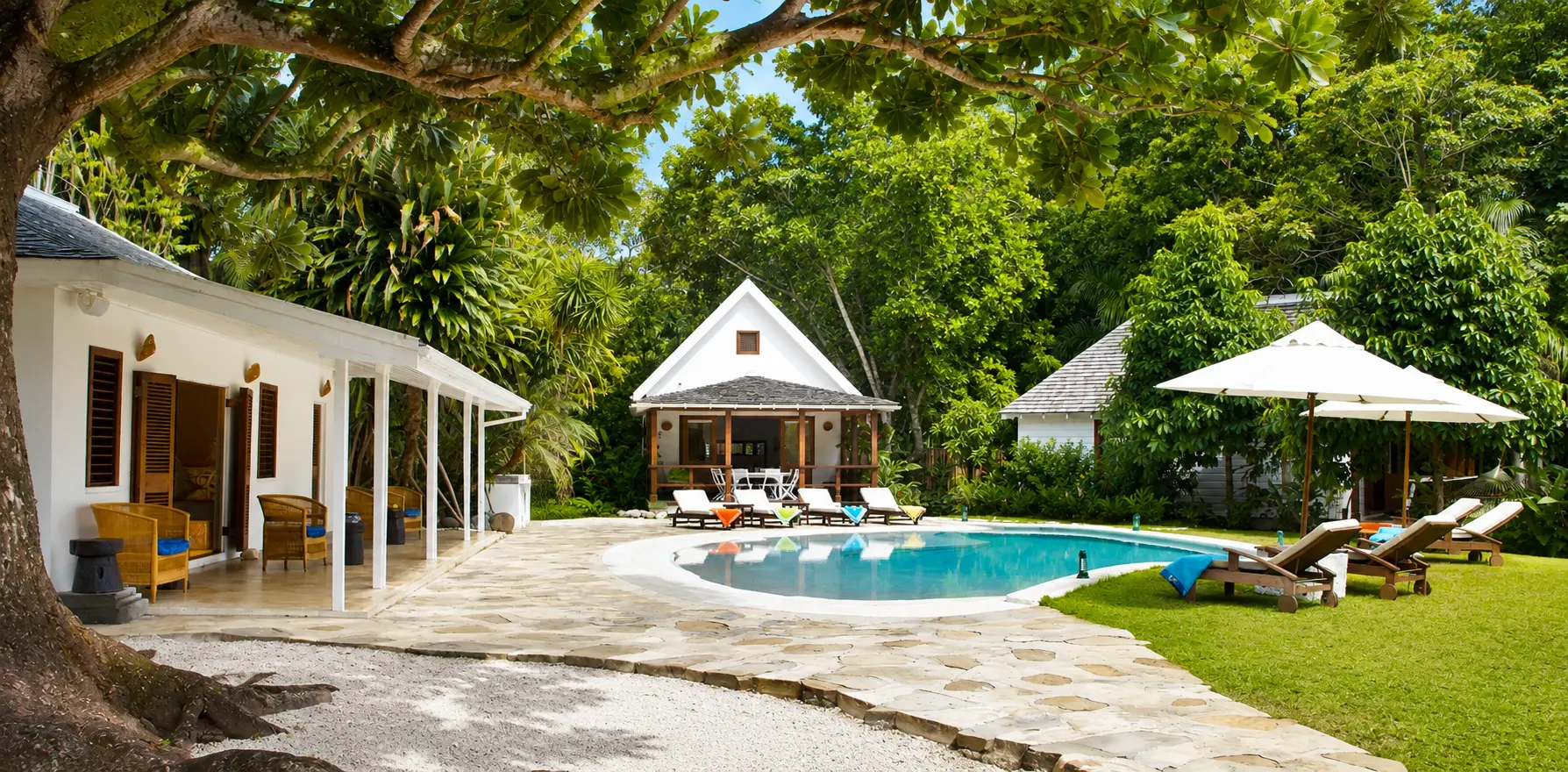 Bedroom inside the Fleming Villa at GoldenEye Jamaica with vaulted ceilings, wooden shutters and views toward the Caribbean Sea.