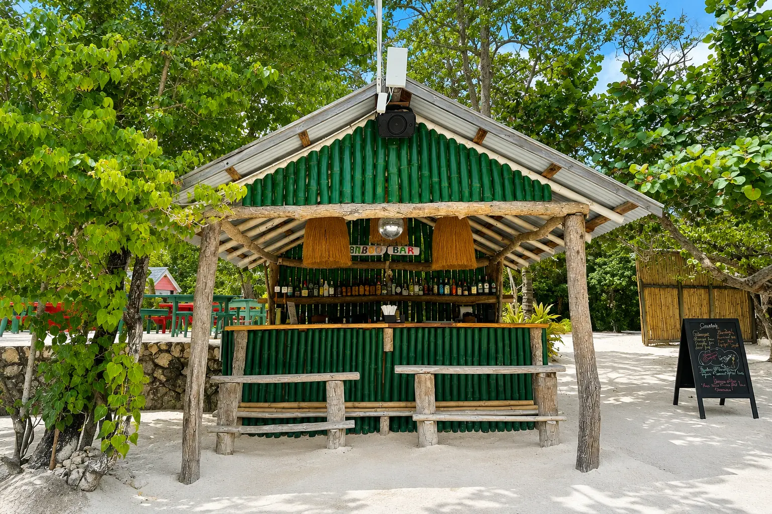 Bamboo Bar on the beach at GoldenEye Jamaica, surrounded by tropical trees and white sand.
